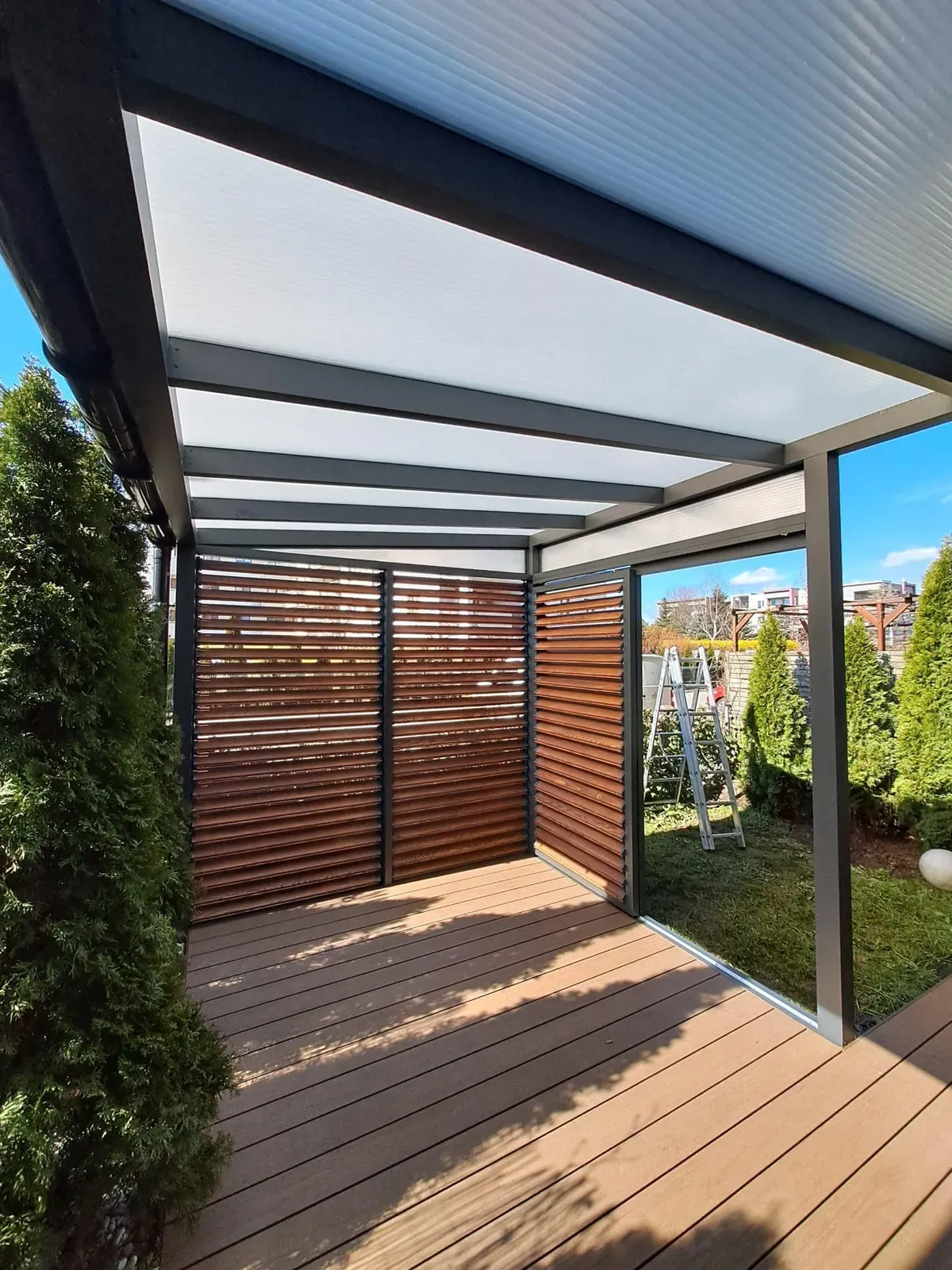 Hliníková pergola s polykarbonátovou střechou nad terasou – realizace Flowgarden
